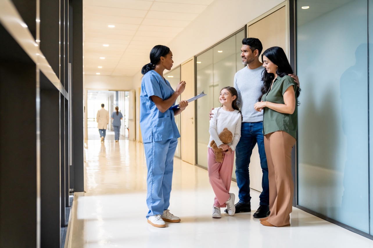 A pediatrician talking with a family in a clinic corridor